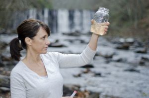 Female researcher checking the water quality from a river