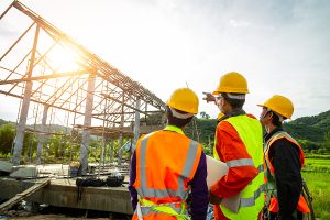 Engineer technician watching team of worker control in Construction workers wearing safety clothing and discussing on construction site