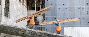 Workers carry boards for the restoration of an old building