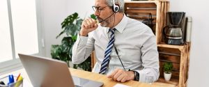 Middle aged man coughing while working