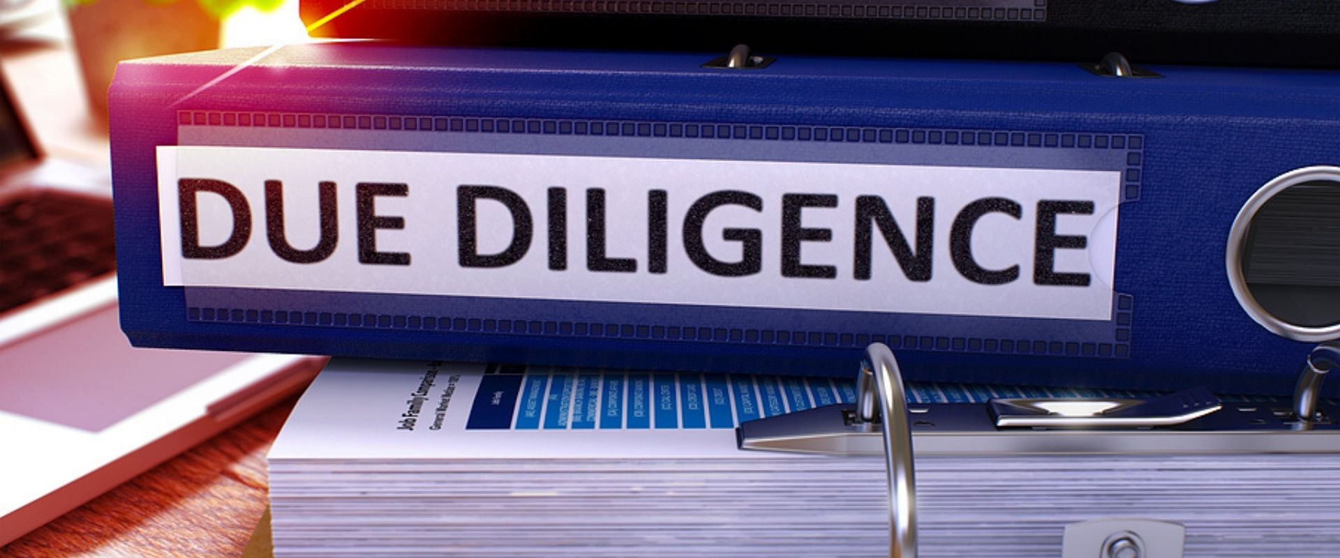 binders sitting on a desk with the words Due Dilligence on them.
