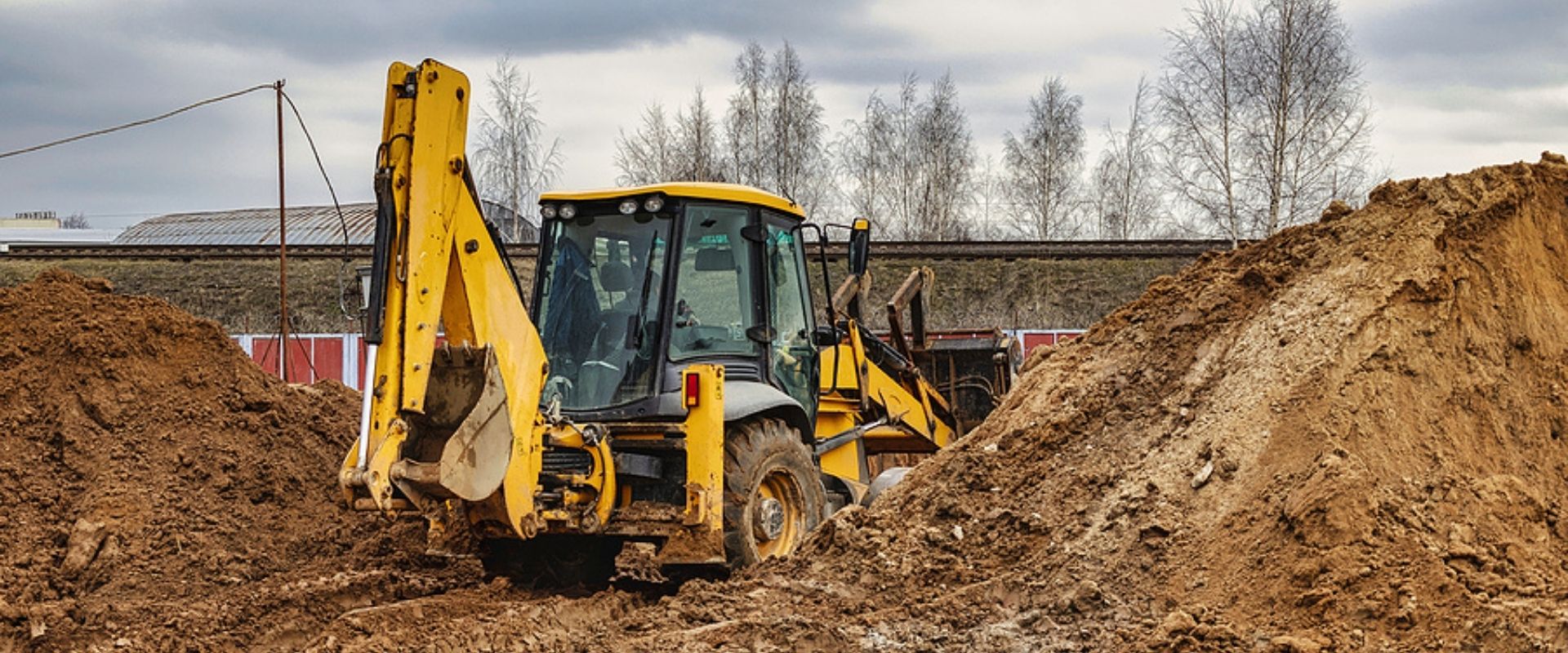 Excavator is working on a construction site against a cloudy sky