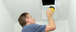 A man with a flashlight inspecting air ducts