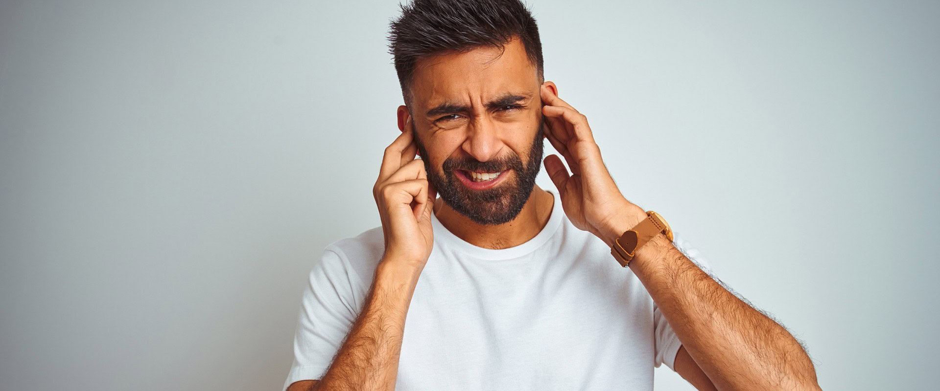 Man closing his ears due to noise pollution.