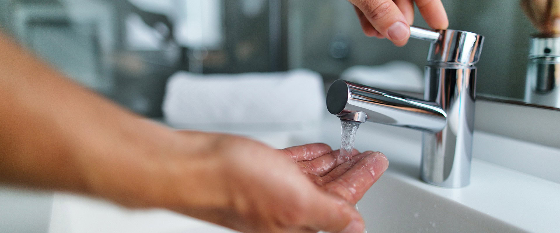 Hand under hotel water sink.