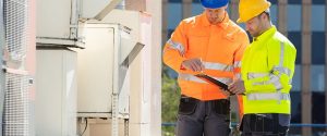 Two environmental assessors check a air conditioning unit.