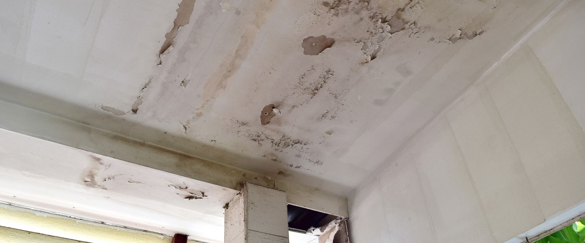 A white ceiling with paint peeling and signs of water damage