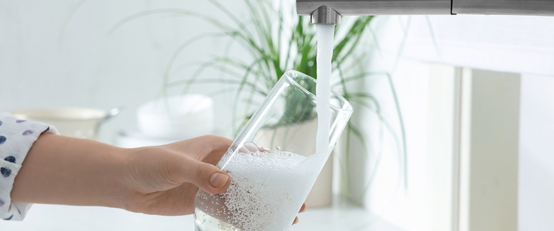 person getting a glass of water from the kitchen sink