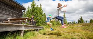 Summer nature side view of children in mid air jumping of a porch landing on grass hill